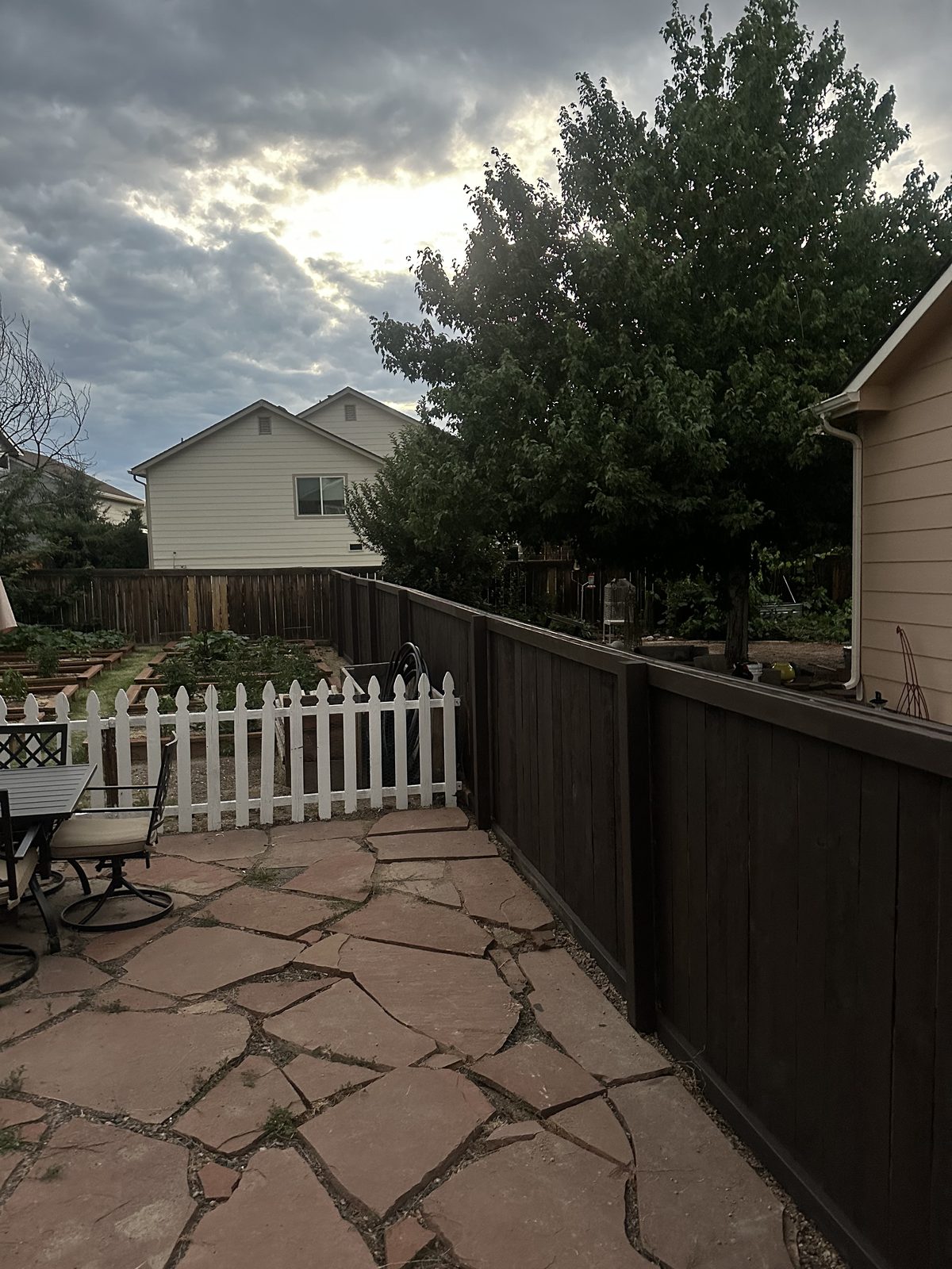 Flagstone patio beside a stained privacy fence and raised garden beds